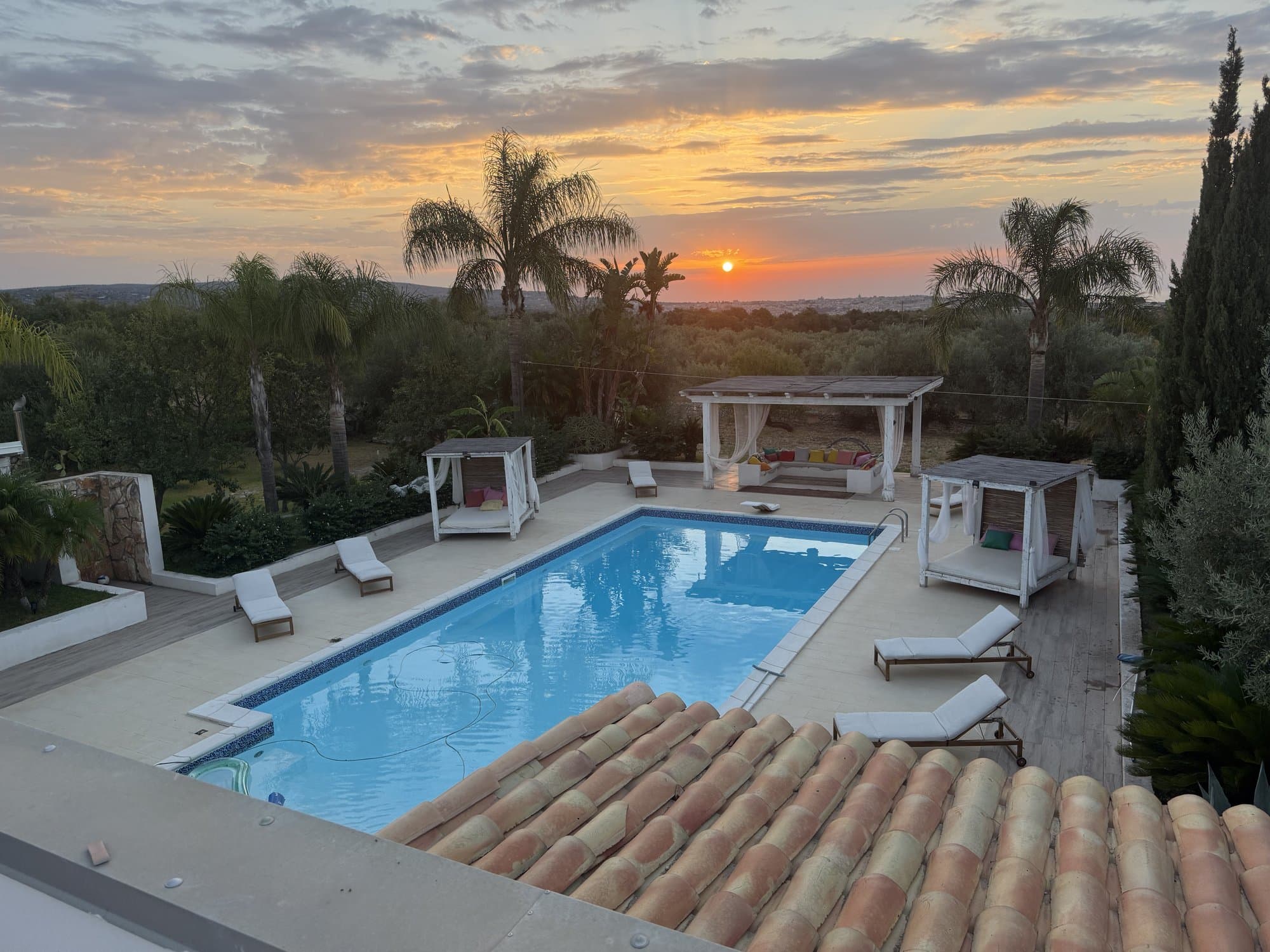 Vue sur la piscine et les jardins depuis le rooftop au coucher du soleil